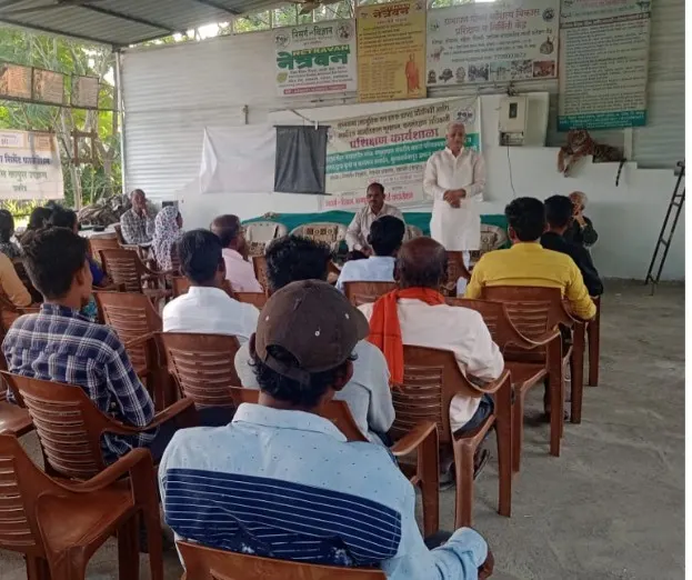 Villagers seated under a shed, listening during a forest rights committee training.