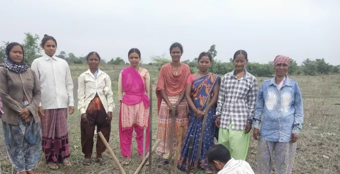 Women and men of a Gram Sabha standing together on their community forest land.